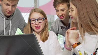 Teenagers studying together at school library, using laptop