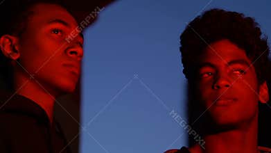 Two Afro-American male hooligans watching burning building at night, fire, crime