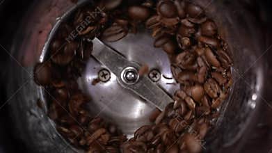 Coffee beans grind in a coffee grinder, barista prepare ingredients for work in slow motion