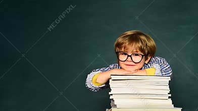 Funny little boy pointing up on blackboard. School concept. School kids against green chalkboard. Learning concept