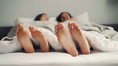 Human feet moving in bed in funny rhythm, couple having fun in bedroom