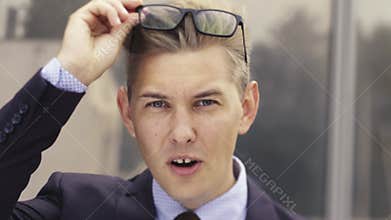 Portrait of shocked businessman. Young handsome Caucasian Man in surprise shoots glasses and looks at the camera.