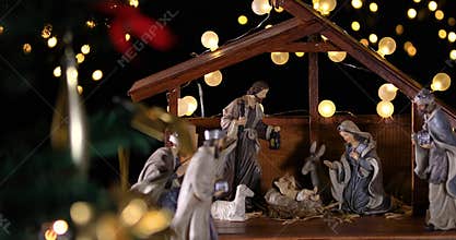 Jesus Christ Nativity scene with atmospheric lights near Christmas tree