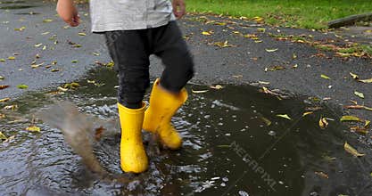 Baby stomping through puddles in yellow rubber boots