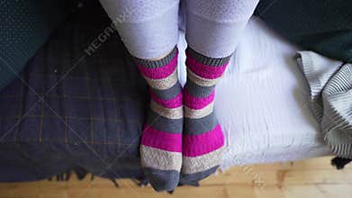 Female legs in brown-pink warm knitted socks close-up on a cozy sofa with a blanket. Life philosophy of Lagom, the