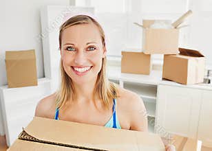 Smiling woman holding boxes after moving