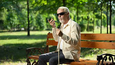Sad blind man holding phone without voice app, inappropriate gadget for impaired
