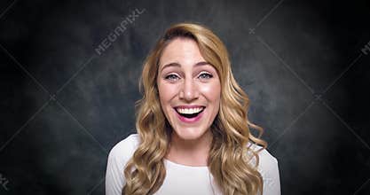 Attractive blonde is surprised and says wow on a dark background.