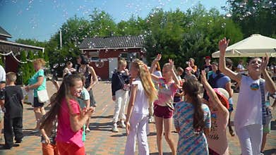 Holiday kids in park, happy children have fun outdoors playing and jumping with soap bubbles while relaxing on summer