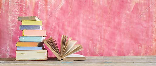 Open Book and stack of multicolored hardback books, reading education, literature,book fair concept. Panoramic format, copy