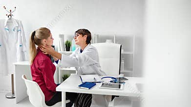 Smiling professional doctor in uniform examining neck and chest checking health of female patient