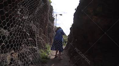 A young woman is afraid of claustrophobia and runs in the aisle between the mountains. Grid for protection against