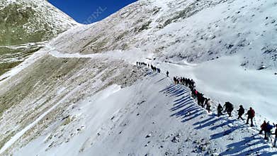 Aerial view from behind. Group of climbers climbing a mountain in winter.