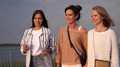 Happy female friends walking and loughing while one is telling a story.