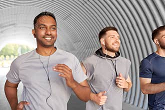 Male friends with earphones running outdoors