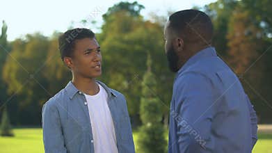 American father and teenage son arguing outdoors, family conflict, communication