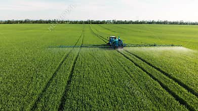 Aerial view of the tractor that irrigates the green field by special installation. The process of spraying field growths
