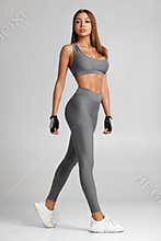 Sexy fitness woman. Beautiful athletic girl on the gray background