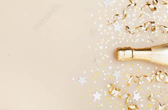 Golden champagne bottle with confetti stars and party streamers top view. Christmas, birthday or wedding background. Flat lay