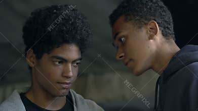 Aggressive Afro-American male teenager threatening boy in dark lane, bullying