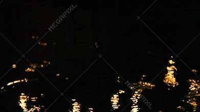 Great background or moving texture. Golden blurry lights shift, ripple, and move atop water as the camera pans left