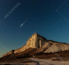 Night star sky and meteor over rock