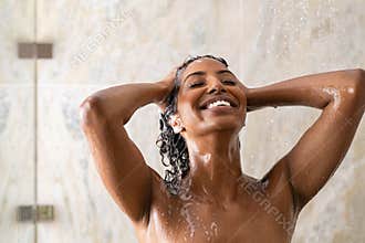 African woman washing hair under shower