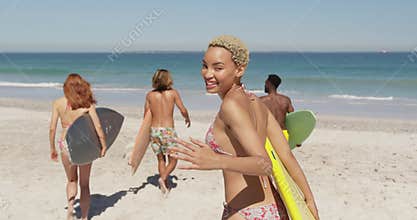 Young adult friends at the beach carrying surfboards 4k