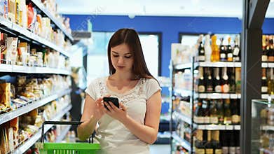 Pretty woman use phone with shopping basket in supermarket, texting sms