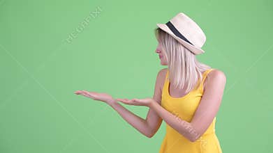 Happy young blonde tourist woman showing something and looking excited