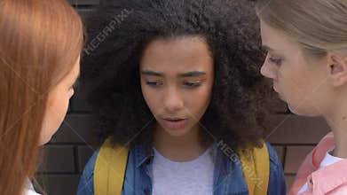 Classmates bullying biracial girl at wall, psychological attack, intimidation