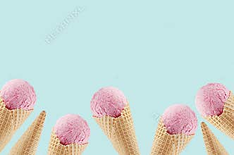 Summer food decorative border of delicious pink ice cream in crisp waffle cones on green background.