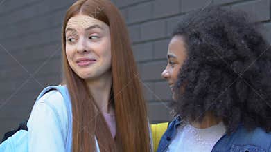 Cruel teenage girls mocking classmate passing by, malicious rumors, bullying