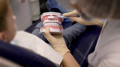 A female doctor shows the child a boy how to brush his teeth. Oral hygiene is very important for dental health.