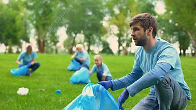 Young eco-activist collecting rubbish in forest with volunteer group, pollution