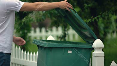 Male citizen throwing garbage in trash can, preventing littering, environment