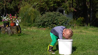 Two years old boy play with water in garden. Wet child splash water on himself