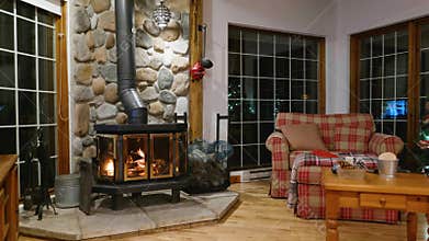 Wood stove fireplace with metal body and glass door in house with cozy interior