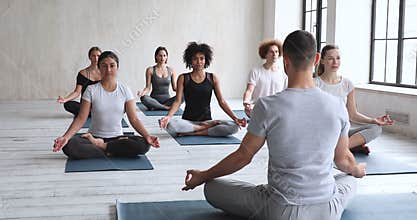 Male coach and multiethnic people seated in lotus position meditating