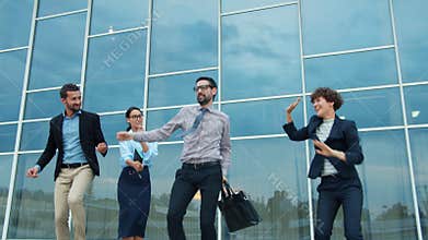 Group of happy businesspeople dancing outdoors in city street having fun together