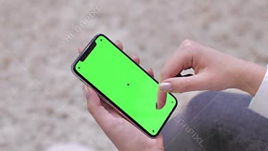 Woman using smartphone watching green screen on mobile phone