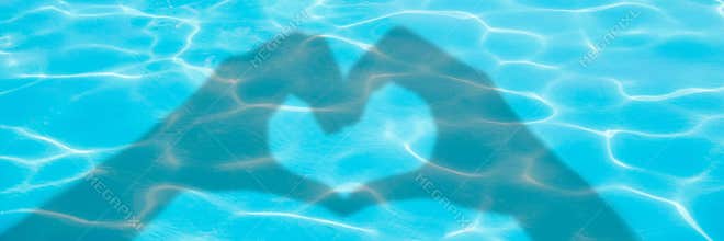 Shadows of hands forming a heart on blue swimming pool water background panoramic valentines day or summer banner