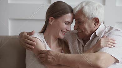 Happy loving senior father embracing young daughter looking at camera