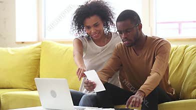 Happy smiling african american couple calculating domestic bills at home