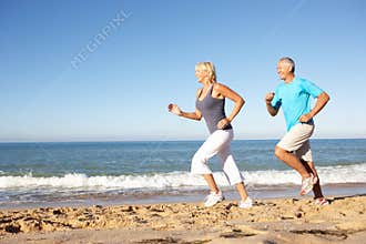 Senior Couple Running Along Beach
