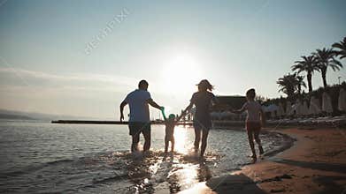 Happy young family have fun walking on beach at sunset. Family silhouette travel holiday.