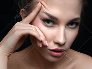 Close up portrait of a beautiful woman toucnig her eyebrow.