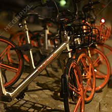 Parked rentable bikes in downtown Berlin, Germany. The bikes are standing in the light of a lantern at evening