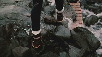 Back view of two young women walking through the mountains river. Tourists hiking together in Iceland.