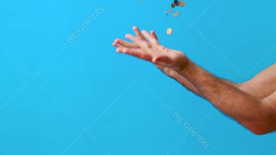 Man hands throw up coins on blue background